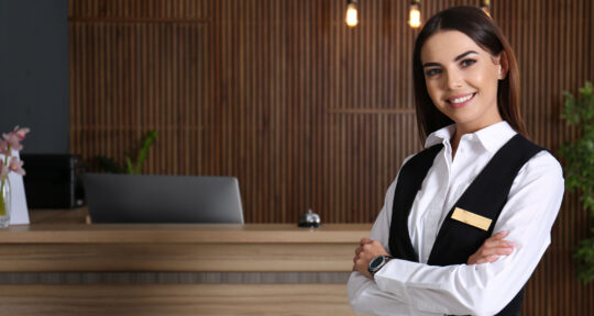 Receptionist sorride di fronte al desk.