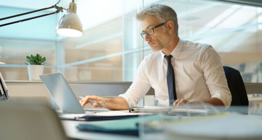 Manager guarda il pc nel suo ufficio