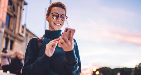 Ragazza che sorride mentre riceve una mail sullo smartphone