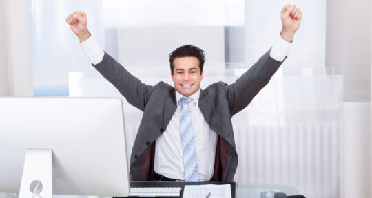 manager felice che esulta davanti al computer